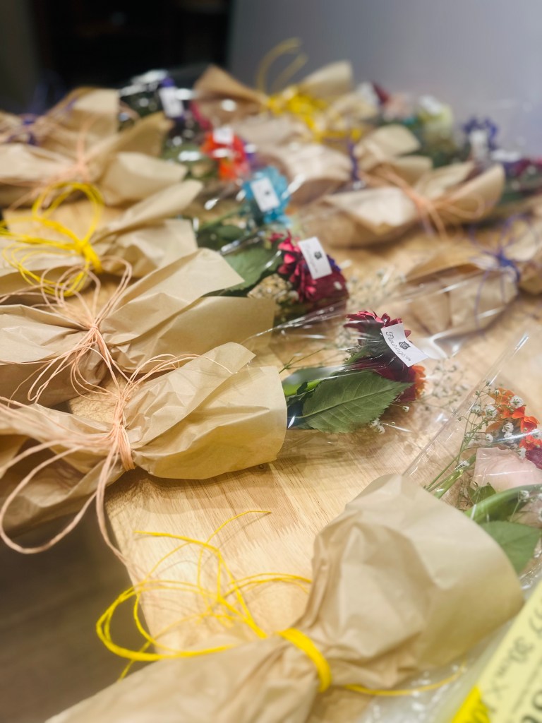 包装された花のブーケが木製のテーブルに並べられている。